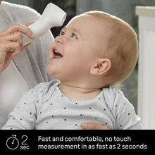 White touchless thermometer near baby's forehead held by caregiver