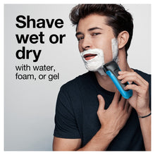 Electric shaver used wet or dry on a man’s face with shaving foam