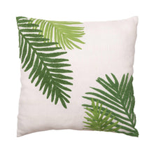 Decorative pillow with white fabric and green palm leaf motif on front