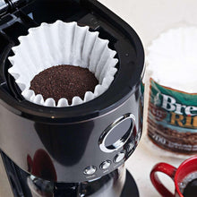White paper coffee filter basket with dark grounds in a coffee maker
