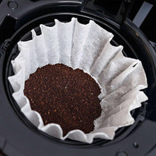Paper coffee filter basket holding dark ground coffee inside a coffee maker