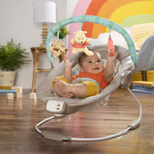 Baby bouncer with Winnie the Pooh plush on seat and activity bar with dangling toys