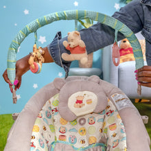 Baby bouncer seat with character pattern and three hanging plush toys on arch