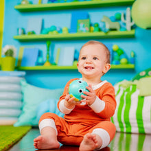 Infant smiling while holding a teal rolling animal ball toy