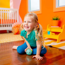 Toddler kneeling and holding a teal rolling animal ball toy