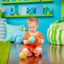 Infant playing with a teal rolling animal ball toy indoors