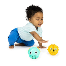 Toddler crawling on white with teal and yellow rolling animal ball toys