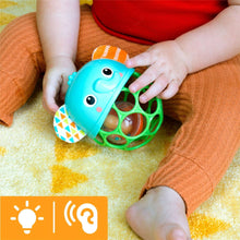 Elephant light-up rattle toy with teal face and green ring, held in hands