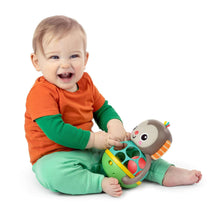 Infant playing with monkey multi-sensory toy: plush head and colorful ball cage