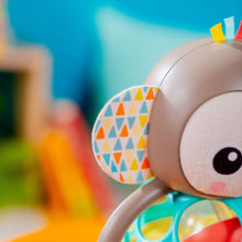 Plush monkey head with patterned fabric ear on a teal and green multi-sensory toy