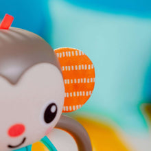 Plush monkey face with gray head and orange patterned ear on a multi-sensory toy