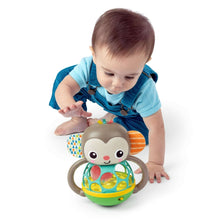 Monkey multi-sensory toy held by infant: plush head, teal ball cage, green base