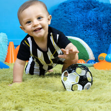 Black and white soccer ball rattle toy on plush surface, held by small hands