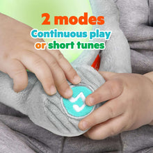 Gray plush elephant soother being pressed with a baby’s hands on soft fabric