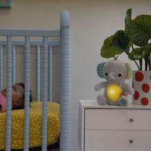 Gray plush elephant soother on dresser shelf with yellow light ball