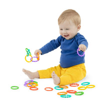 Baby sitting with colorful interlocking loop link rings, including green, purple, yellow, and orange