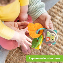 Hands holding a colorful textured key toy with monkey face details