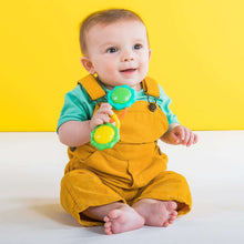 Baby holding green and teal barbell rattle toy with orange and yellow accents