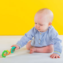 Baby playing with small barbell rattle toy with green and teal ends and orange parts