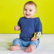 Baby wearing plush wrist rattle teether with white-and-blue animal face on green strap