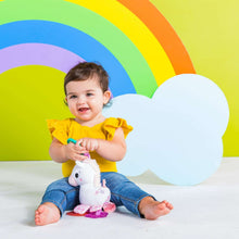 Unicorn plush clip-on toy on toddler in yellow top, teal handle visible