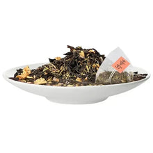 White bowl of loose black tea with a pyramid tea bag and tag