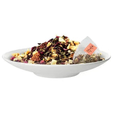 White bowl of loose tea with a pyramid tea bag and tag