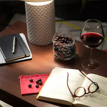Wine and chocolate snack pieces on a wooden table with glasses and notes