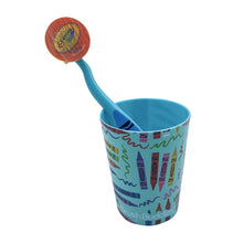 Toddler toothbrush with soft bristle head resting in patterned rinse cup