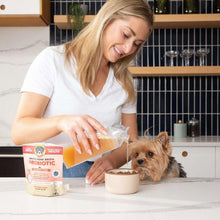 Woman preparing a bowl for her dog with a bone broth probiotic powder pouch