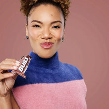 Wrapped Built Puff protein bar held in fingers near face