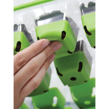 Green silicone pop-out cells in seed tray being lifted by a hand