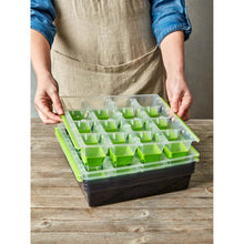 Seed starting tray with green cell inserts, held by hands