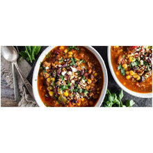 Bowl of dark red kidney bean chili topped with herbs and chopped vegetables