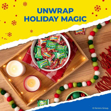 Butterfinger candy bars in green wrappers in a bowl on a wooden surface.