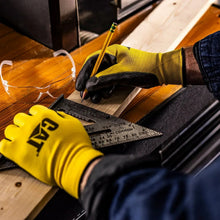 Yellow and black work glove gripping wood, black reinforced fingertips