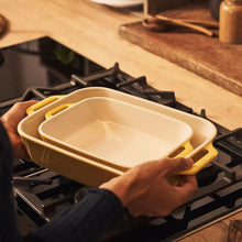 Yellow rectangular stoneware baker set on stovetop with two nested trays