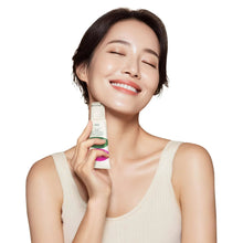 Guasha neck cream tube held near face, beige bottle with pink and green label