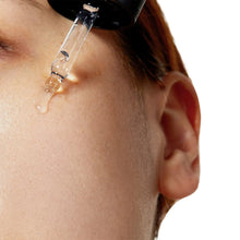 Niacinamide serum droplet on cheek skin with applicator nozzle