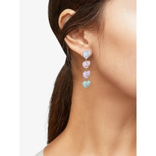 Dangling pastel heart charm earrings on ear with gold hooks