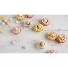 Milk chocolate mini eggs in pastel cupcake-style shells on a white surface