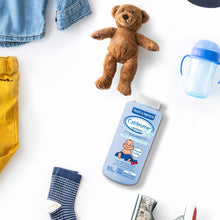 Baby powder bottle with teddy bear and baby socks on a clean background