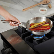 Triply stainless steel skillet on gas burner, sautéing vegetables