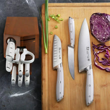 Stainless knife set with white handles and wooden block on a cutting board