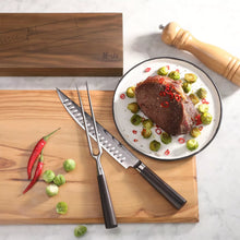 Carving knife and fork with stainless blades and dark handles on wooden board