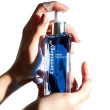 Facial oil bottle held in hands with white dropper and deep blue liquid