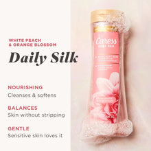 Caress Daily Silk body wash bottle with gold cap, shown with pink foam.