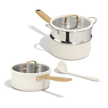 White ceramic saucepan set with stainless steel lids, wood-tone handles, and steamer