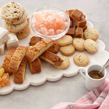 Assorted lemon and chocolate biscuits on a white platter with a small cup