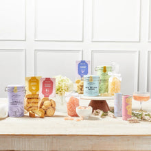 Set of decorative cookie tins with assorted biscuits and chocolates on a shelf
